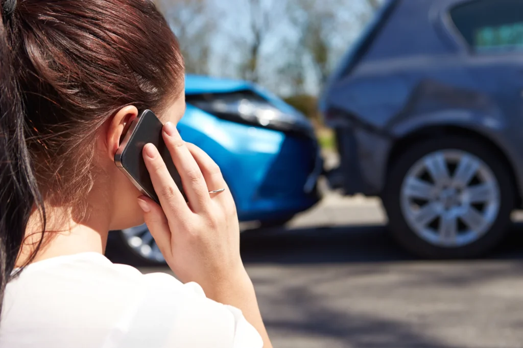 Mujer hablando por teléfono junto a coches dañados tras un accidente de tráfico